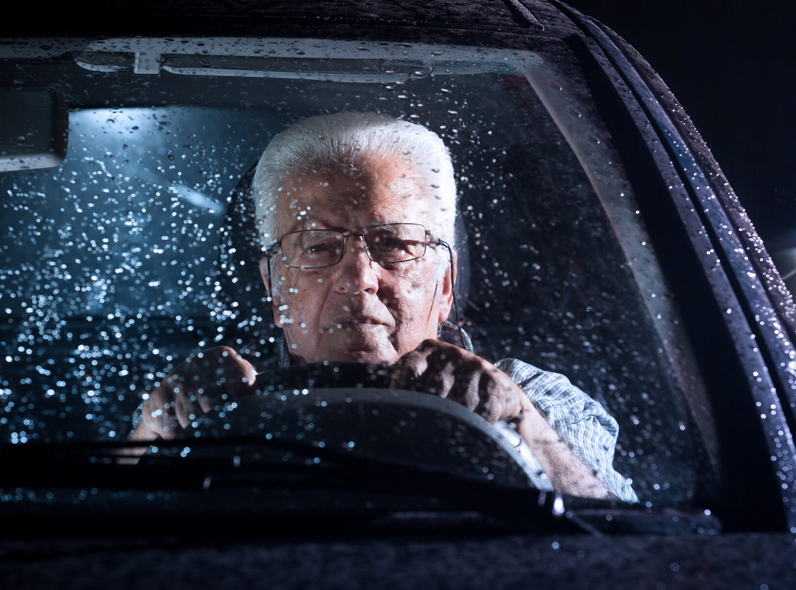 Confident Senior man driving in the rain at night