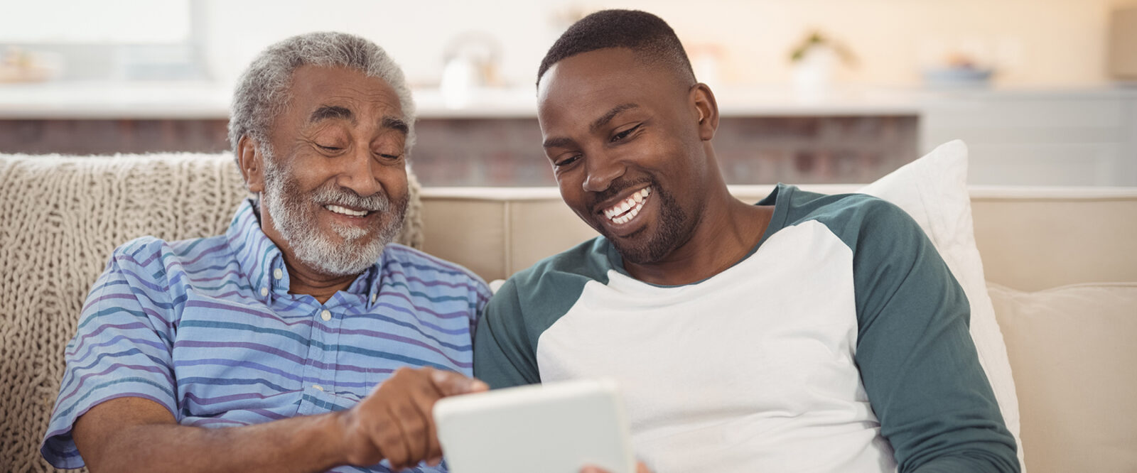 Smiling father and son using digital tablet in living room