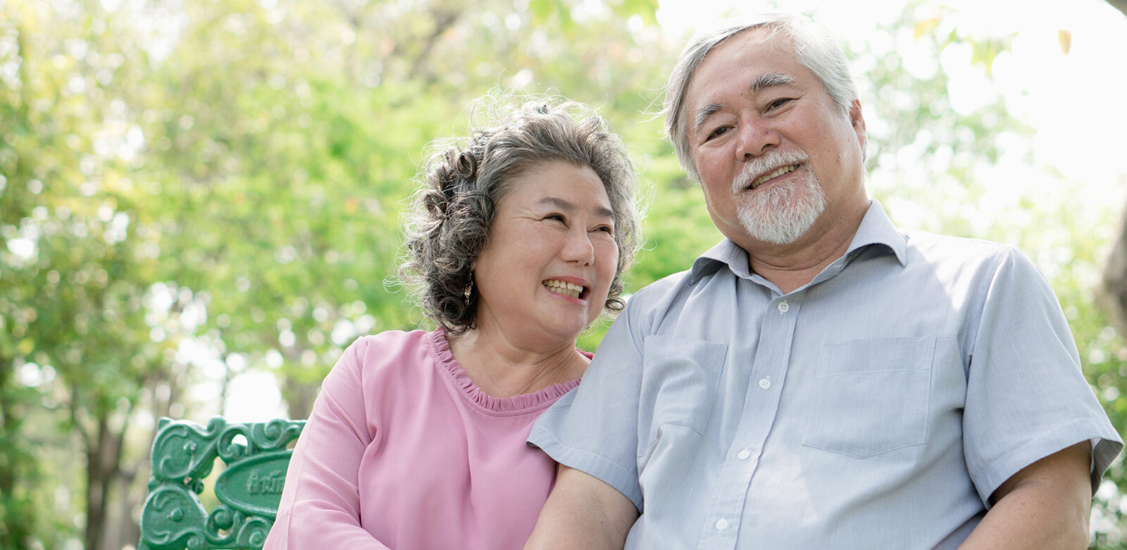 Asian healthy senior couple relaxing seated in the park together