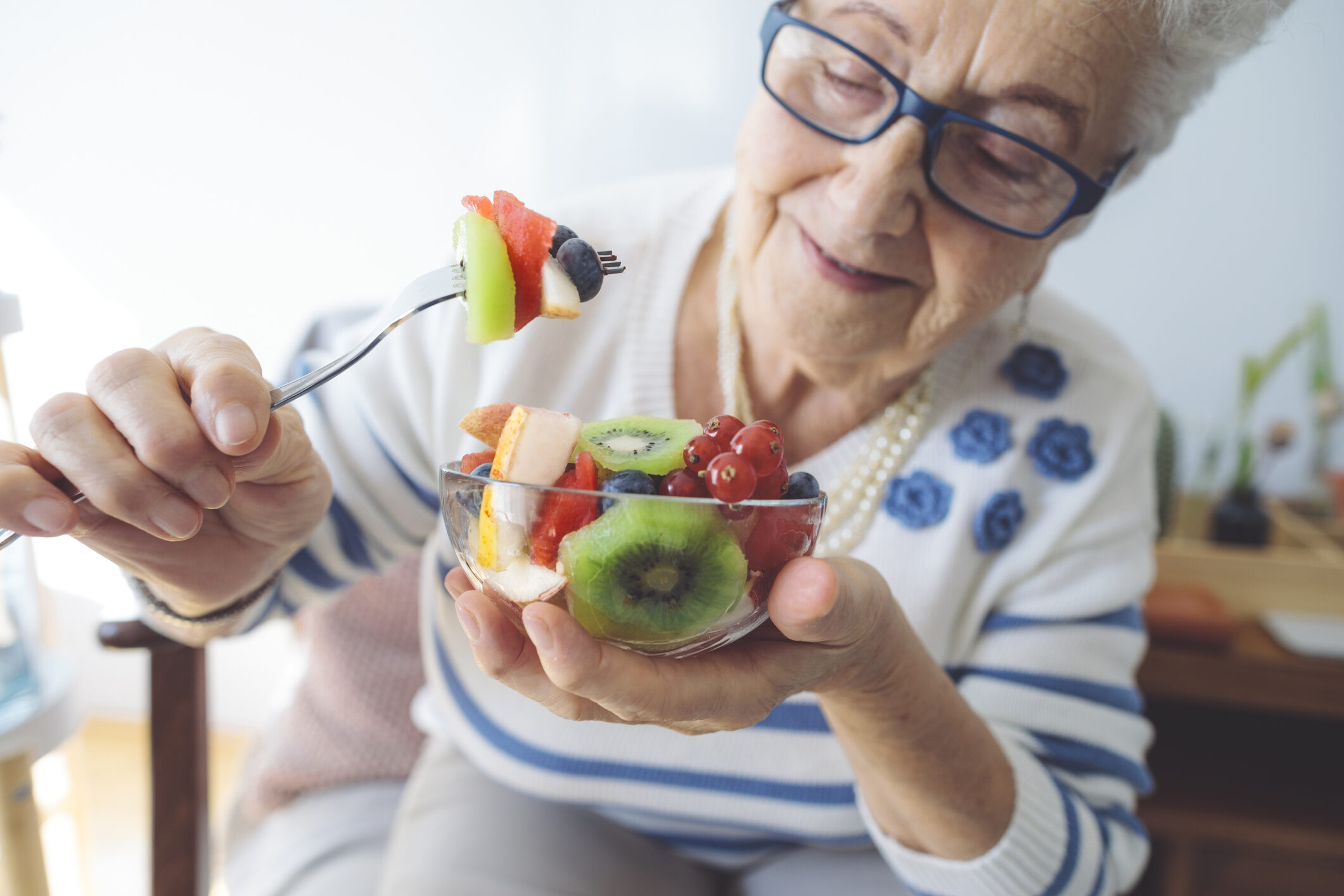 Senior woman at home eating fresh fruit