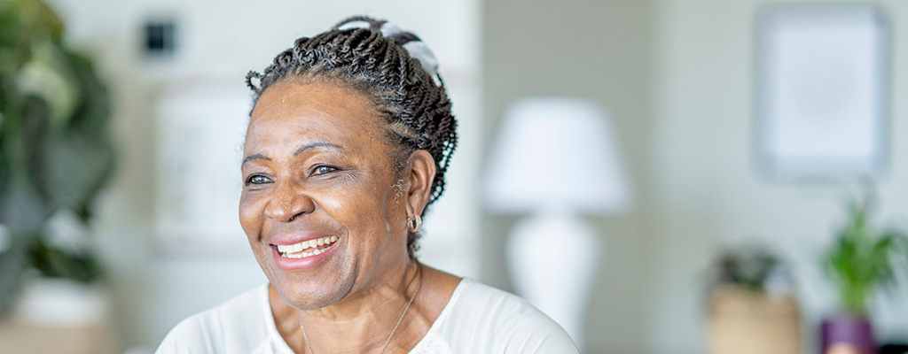 A senior woman smiles for portrait in her home.