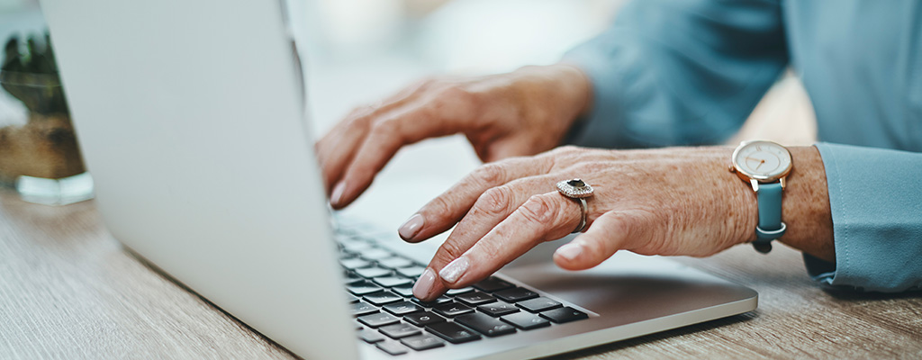 close up of senior woman typing on her laptop